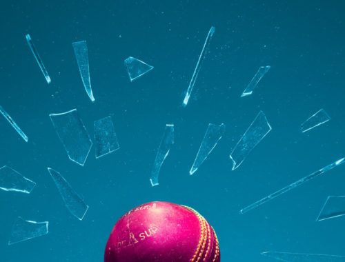 Glass shattered by a red ball against a blue background