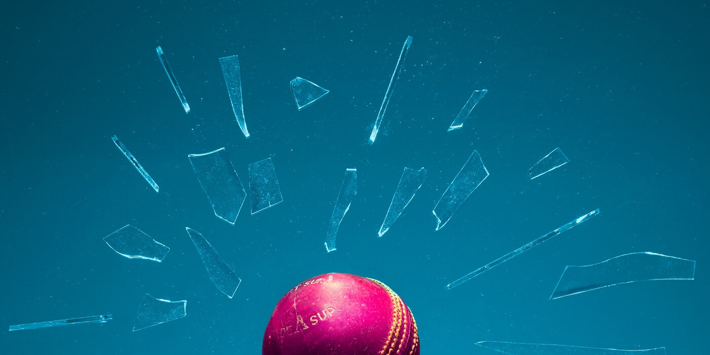 Glass shattered by a red ball against a blue background
